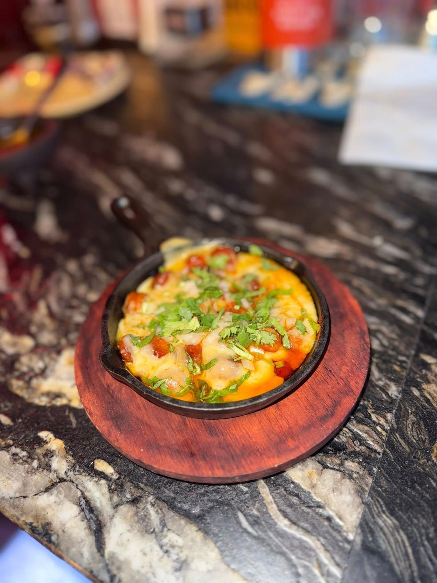 A sizzling skillet topped with cheese and green onions